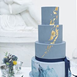 Pieces of edible gold leaf on light blue background, flat lay